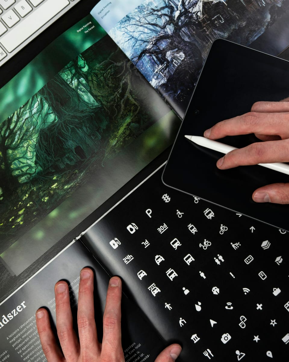 Otwarte książki o projektowaniu, iPad i rysik w dłoni